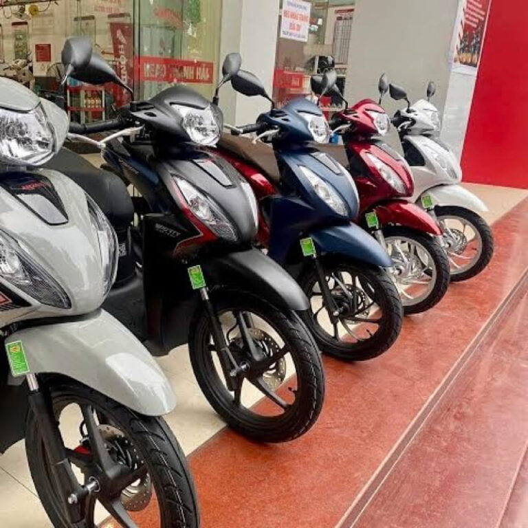 Dãy xe tay ga nhiều màu xếp cạnh nhau phía trước cửa hàng.